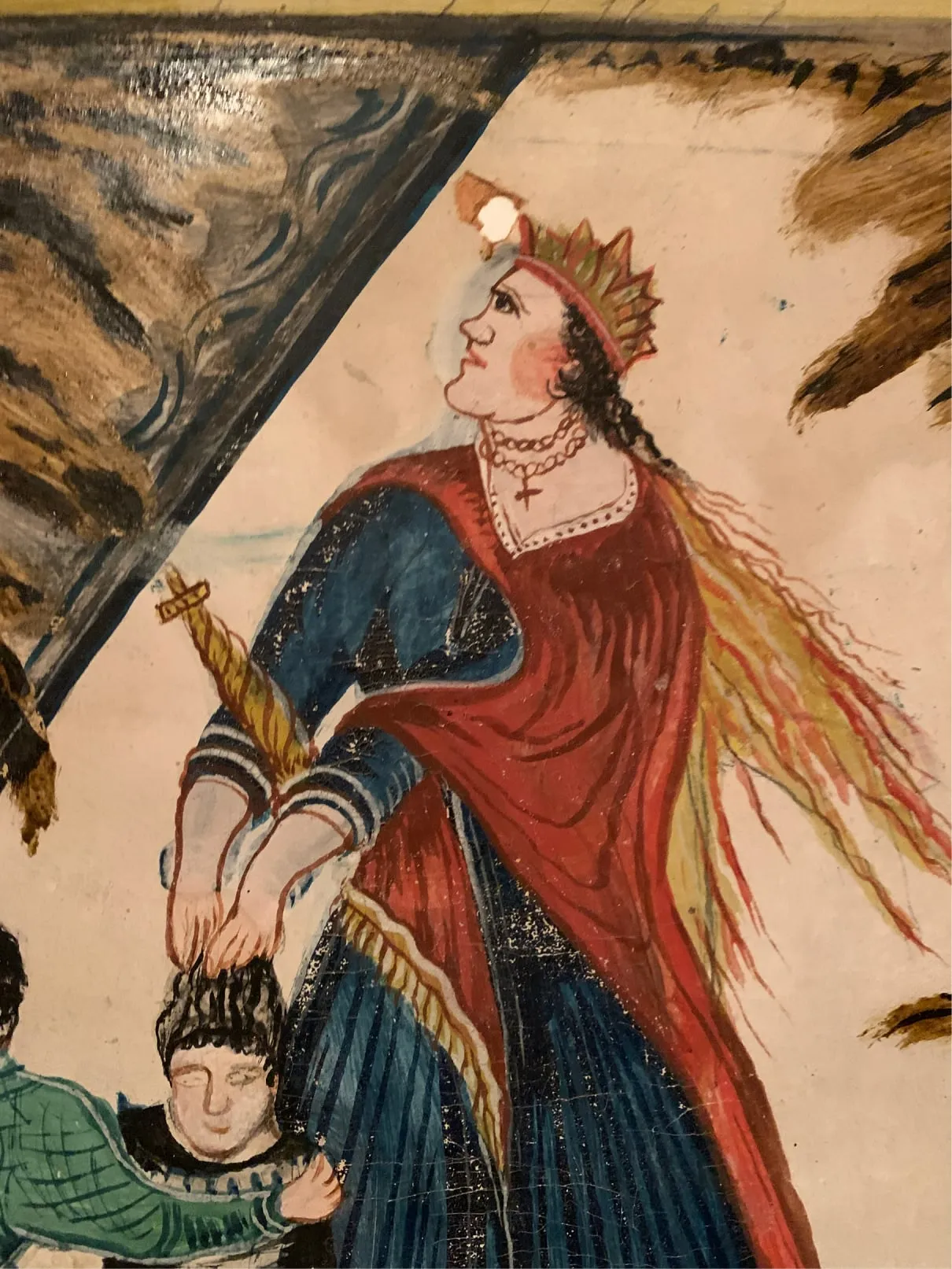 Painted folk-art image of a crowned woman in red and blue holding a cross-shaped object and a child