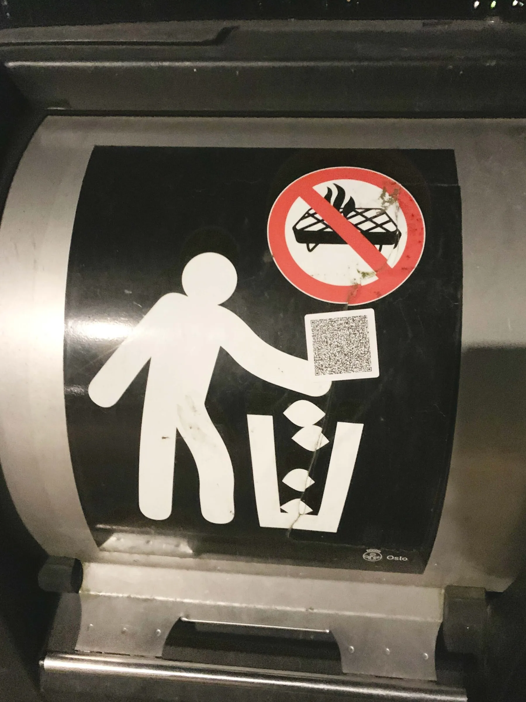 Public waste bin with a pictogram of a person littering and a QR code sticker added